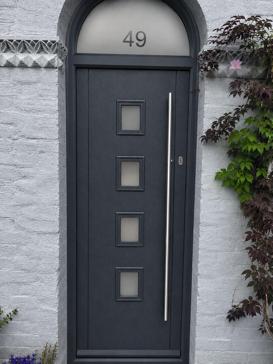 Anthracite grey composite front door with four square glazed panels and a long bar handle, fitted by OakStone