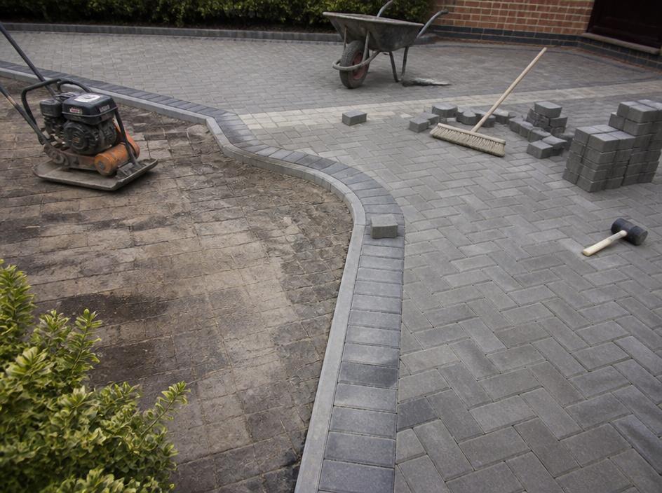 Driveway being relaid, with new block paving next to the old worn surface