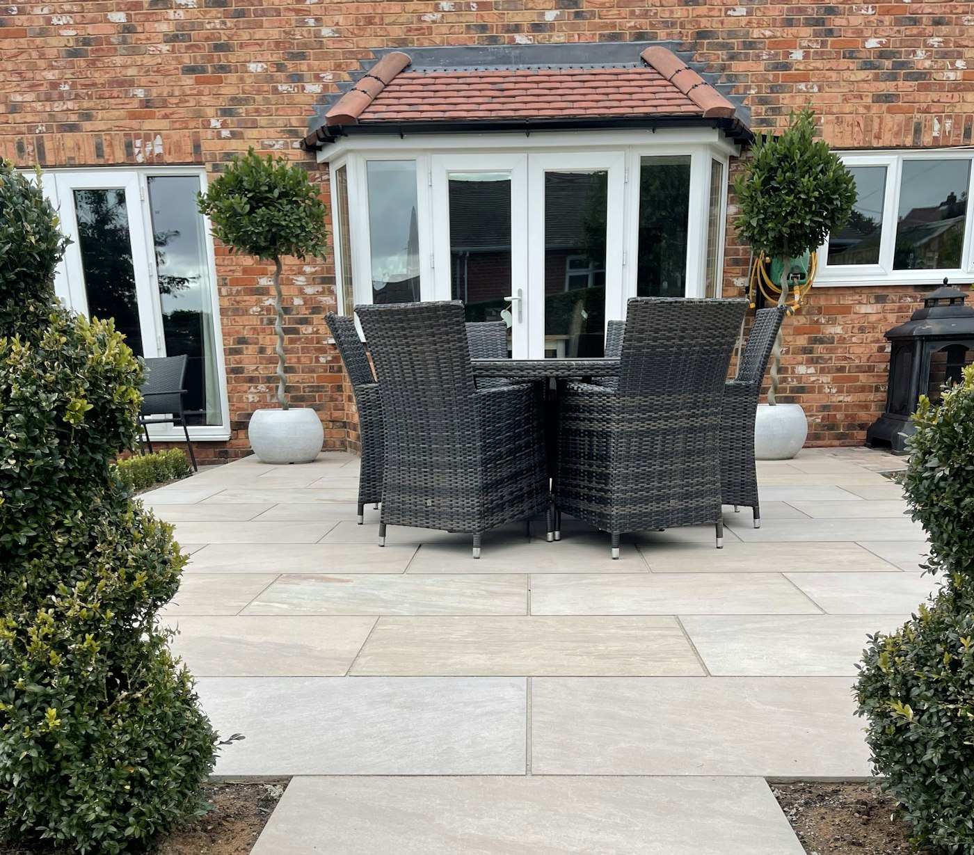Landscaped English garden with striped lawn, stone edging and paved terrace